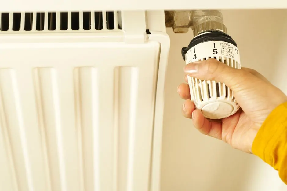 Ruka nastavuje termostatickou hlavici na radiátoru
